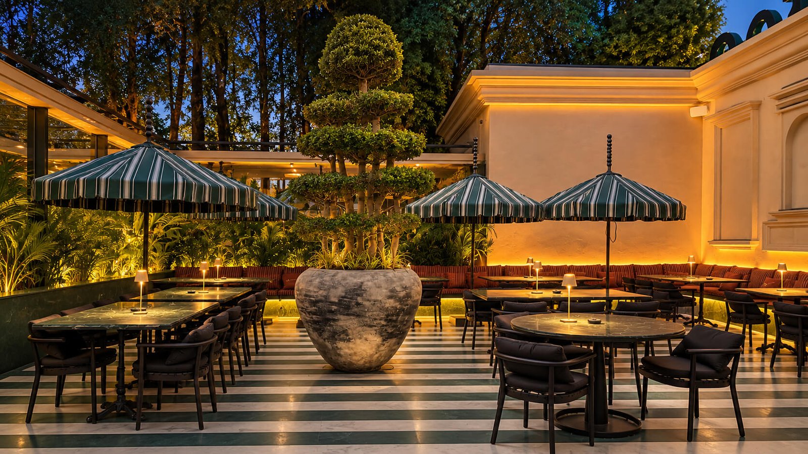 Mood-lit café interior with marble tables, gold lamps, and a floral ceiling grid